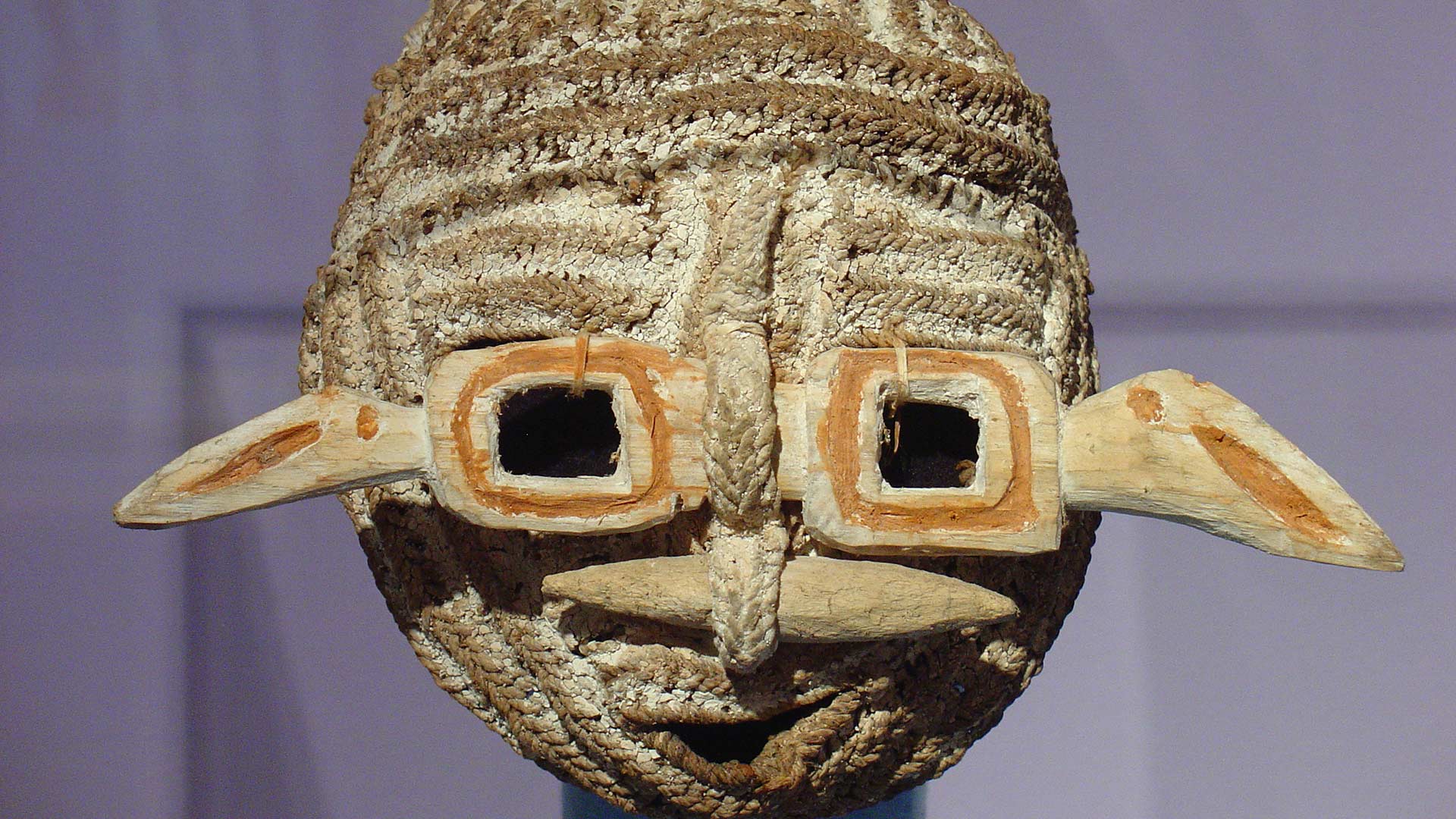a crafted mask made of wood and another woven material