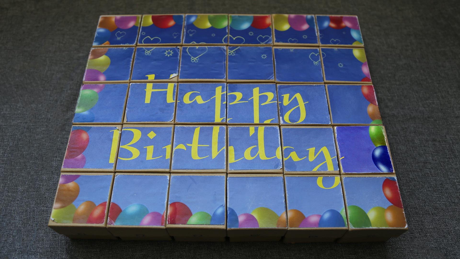 A grid of small boxes with a happy birthday message with balloons printed on the top of the boxes